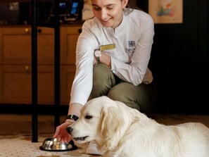 A person in a white coat with a name tag, interacting with a dog. - Square Lodge Hotel La Roche Sur Yon - Handwritten Collection (La Roche-sur-Yon)