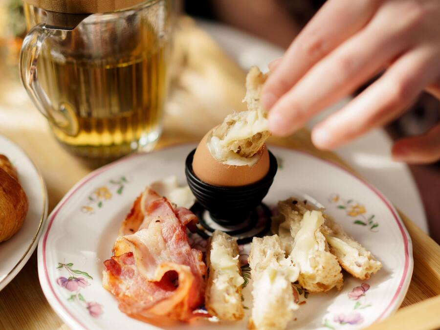 A plate with a poached egg, bacon, and bread.
