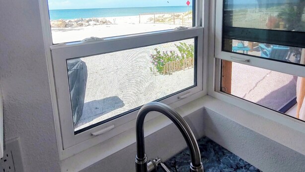 A bathroom with a window offering a view of a beach and ocean. - Manasota Key Beach Cottage Just Thirty Steps from the Beach (Englewood)
