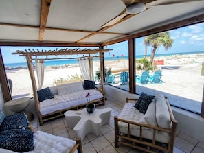 Une chambre située en bord de mer, avec un plafond en bois, un canapé confortable, une chaise en bois et une vue sur la plage et l’océan.