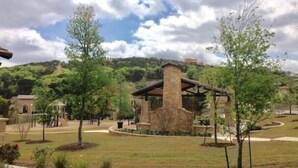 A landscaped area with a stone structure, pathways, and trees.