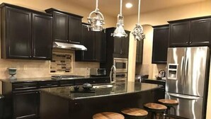 A modern kitchen with dark cabinetry, stainless steel appliances, and a central island with bar stools.