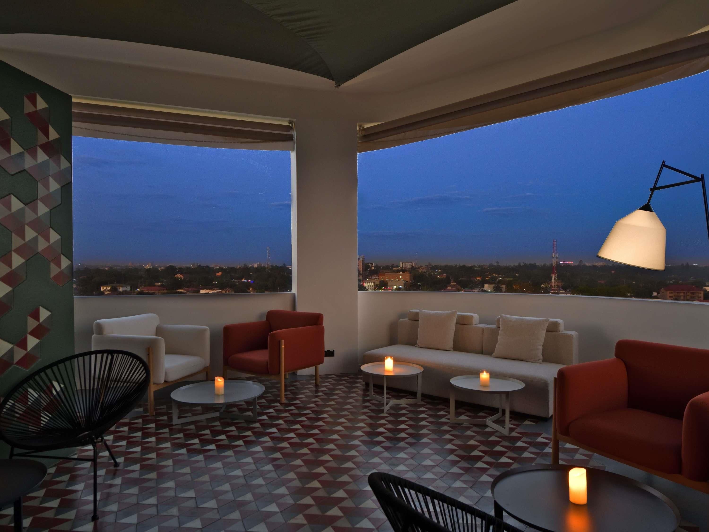 Terraço no telhado com sofá, cadeiras, mesas e um abajur.