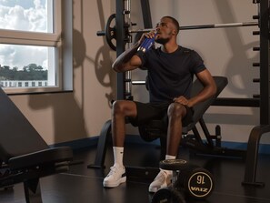A gym with weightlifting equipment, a bench, and a window with a view. - Novotel Lubumbashi (Lubumbashi)