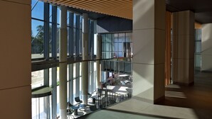 A modern interior with large windows, a mezzanine level, and a wooden slatted ceiling. - Novotel Lubumbashi (Lubumbashi)