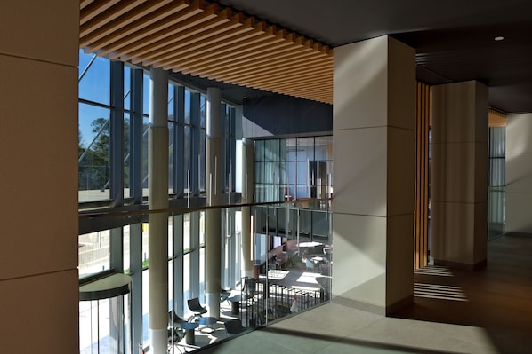 A modern interior with large windows, a mezzanine level, and a wooden slatted ceiling. - Novotel Lubumbashi (Lubumbashi)