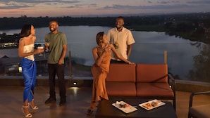 A group of people on a terrace with a lake view, a table with food, and a sofa. - Novotel Lubumbashi (Lubumbashi)