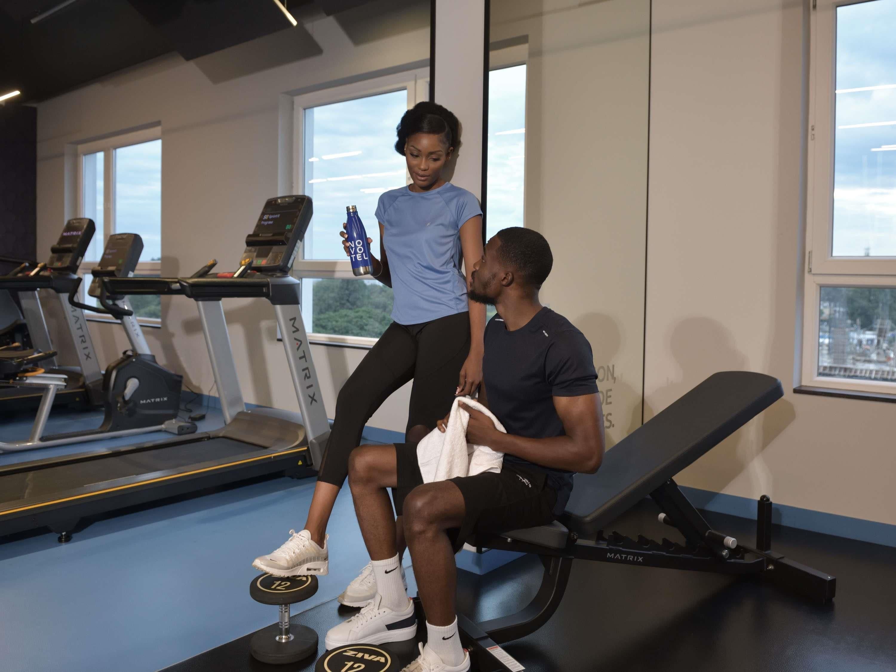 Un gimnasio con cintas de correr, una banca y equipo para levantar pesas.