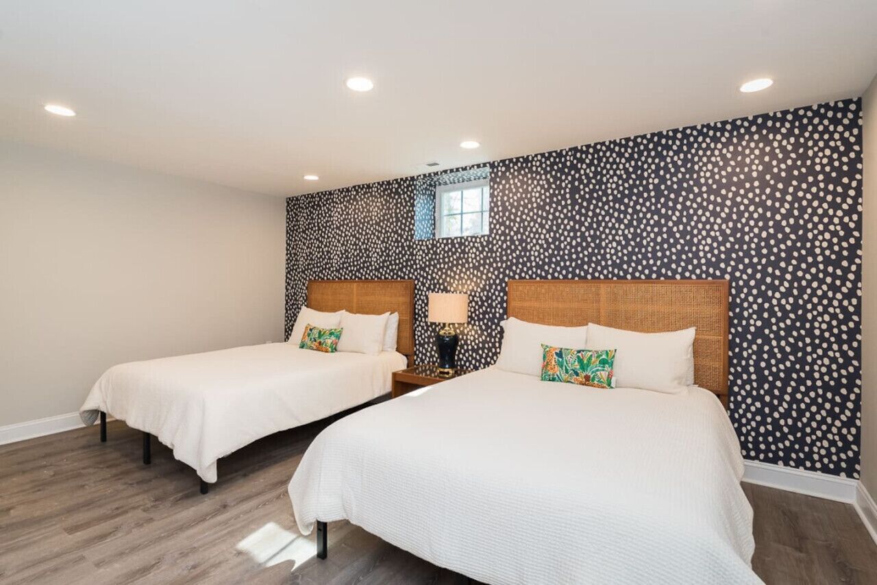 A hotel room with two beds, a window, and a patterned wall.