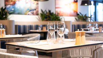 A restaurant interior with tables set for dining, clear glassware, and a modern design.