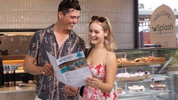 A man and a woman standing in a cafe, holding a menu.