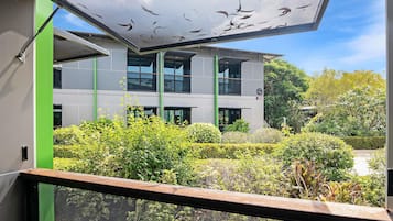 A modern building with a large glass facade, surrounded by well-maintained greenery and a clear sky.