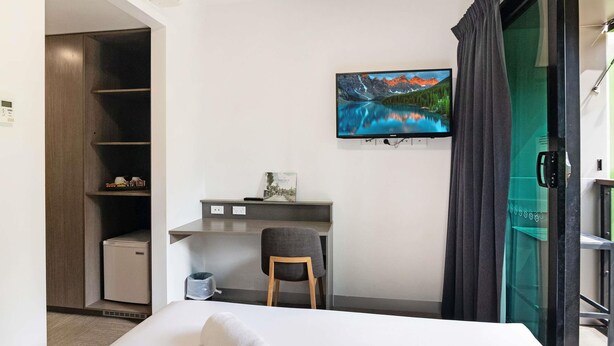 A hotel room with a bed, a desk, a chair, a TV, and a view of a mountain landscape. - Ibis Darwin Airport Hotel (Eaton)