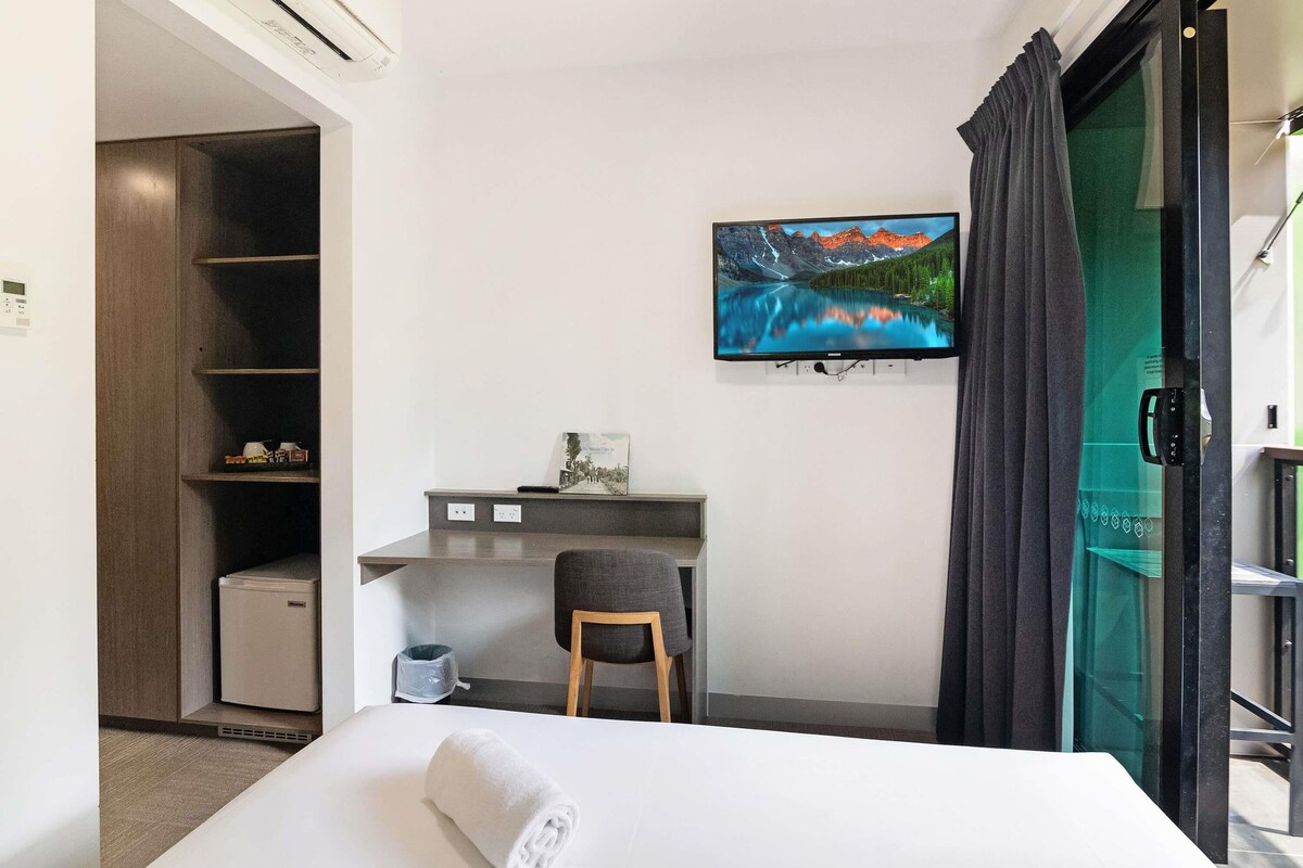 Habitación de hotel con cama, escritorio, silla, televisor y vistas a un paisaje montañoso.