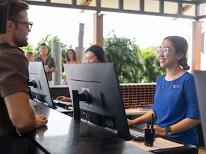A reception desk with a computer monitor, a name tag, and a walkie-talkie. - Ibis Darwin Airport Hotel (Eaton)