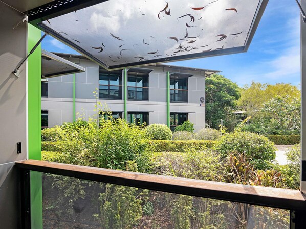 A modern building with a large glass facade, surrounded by well-maintained greenery and a clear sky. - Ibis Darwin Airport Hotel (Eaton)