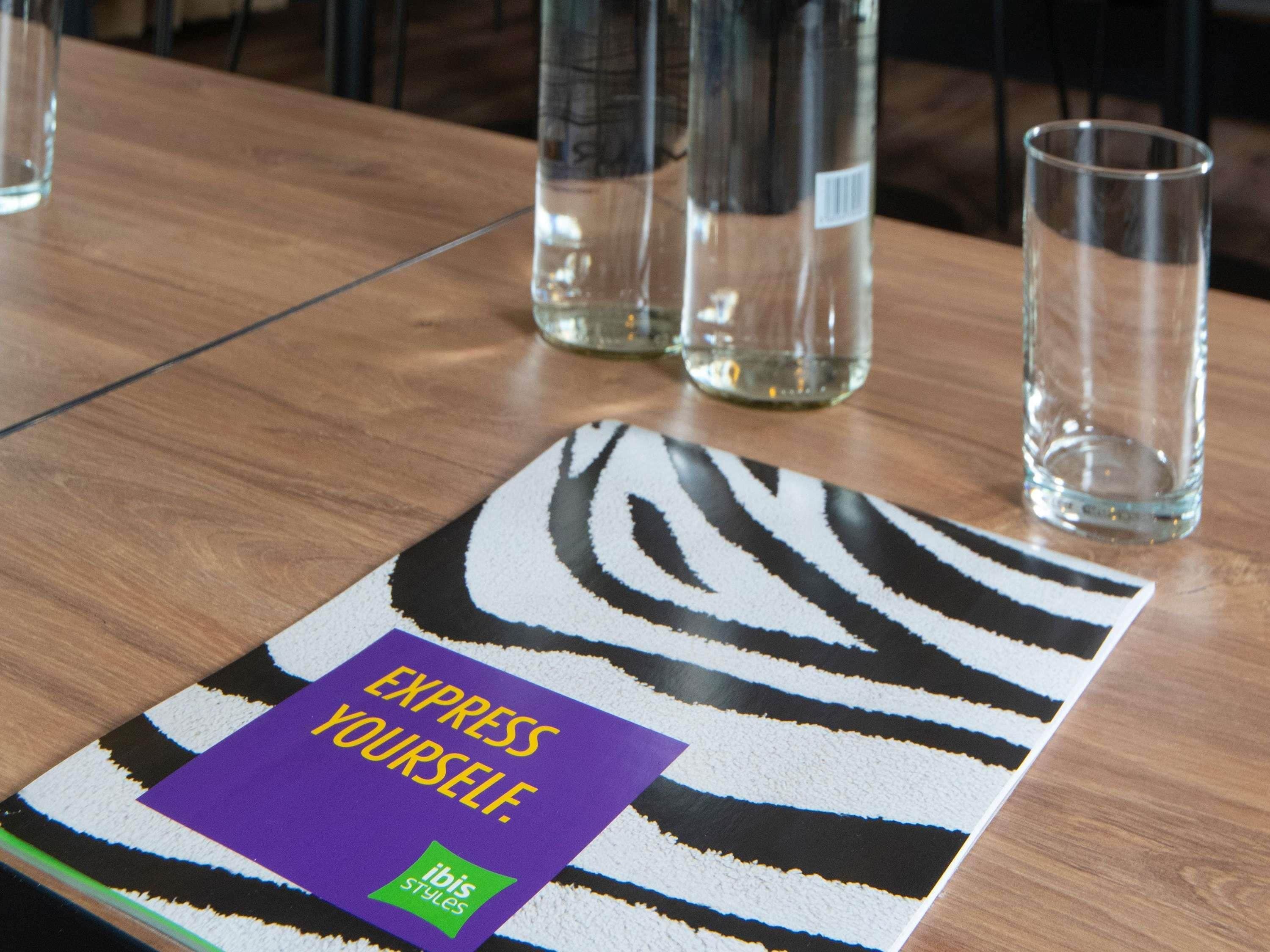 A table with a zebra-striped placemat, a glass, and a bottle.