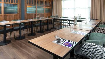 A conference room with a long table, chairs, and a large window with curtains.