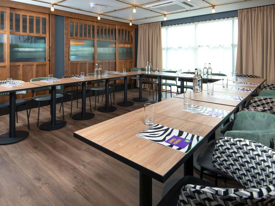 A conference room with a long table, chairs, and a large window with curtains.