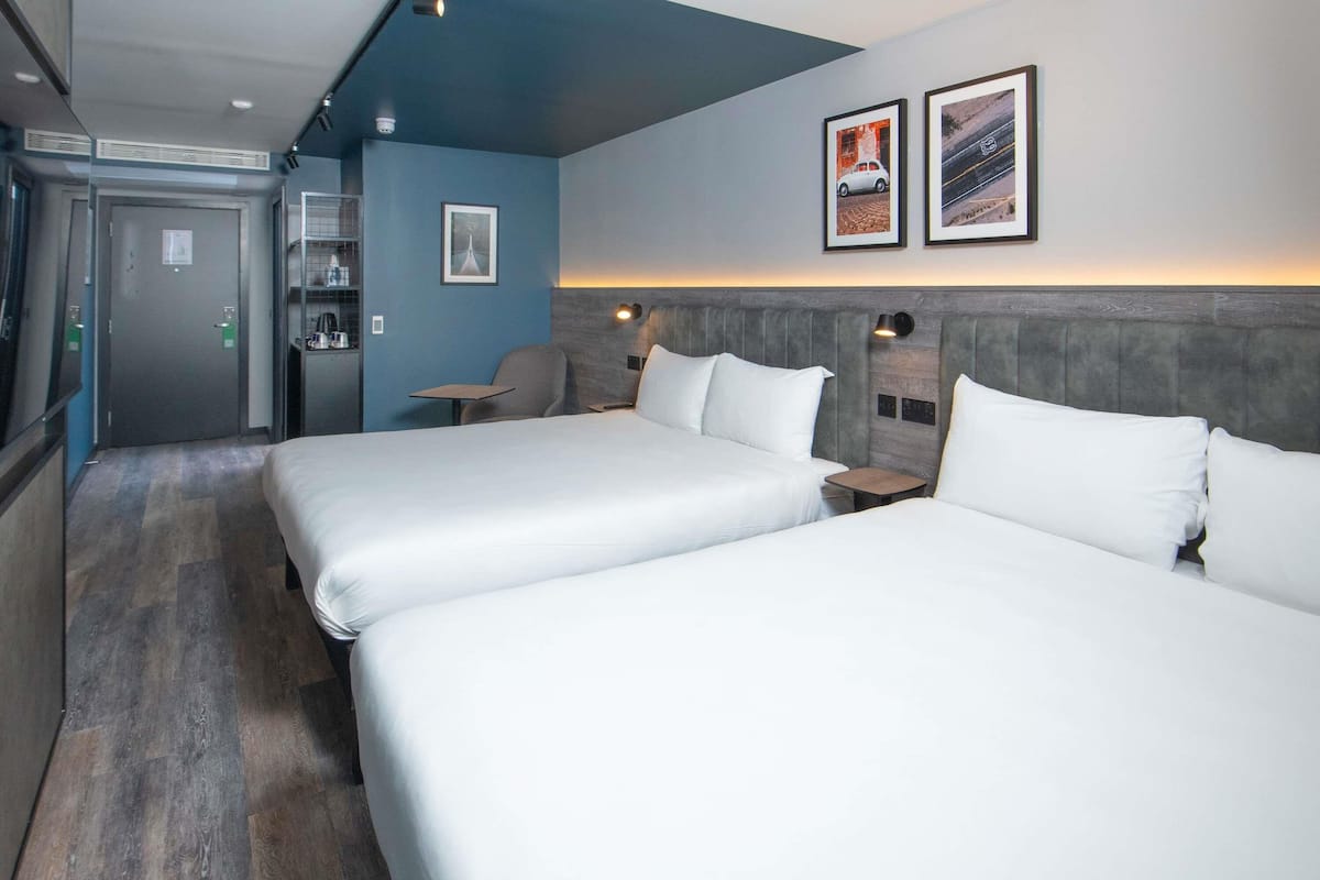 Een hotelkamer met twee bedden, een bureau, een stoel, een tafeltje en een deur.