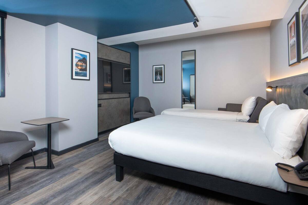 Een hotelkamer met een groot bed, een tafeltje, een stoel en een spiegel.