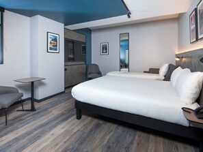 Una habitació d'hotel amb un llit gran, una taula petita, una cadira i un mirall.