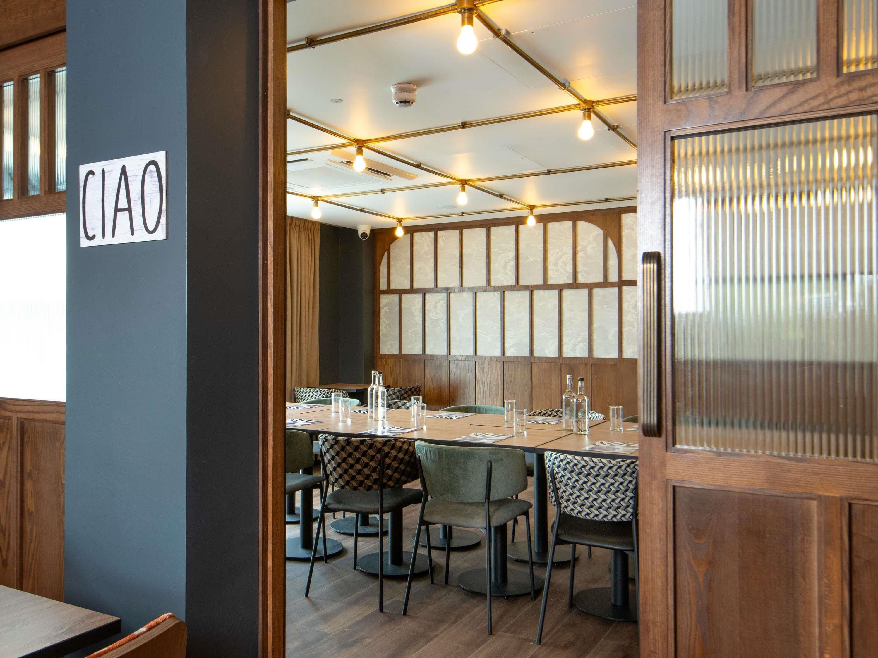 Ein Restaurantinterieur mit einem für das Essen gedeckten Tisch, einem Schild mit der Aufschrift 'CIAO' und einer Holzbalkendecke.