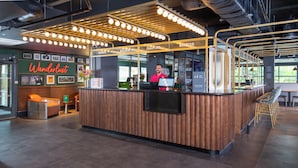 A modern reception area with a wooden counter, a digital screen, and a seating area with chairs.