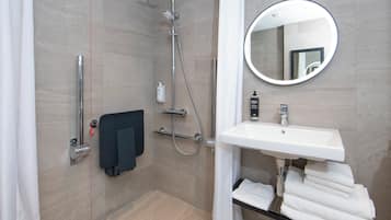 A modern bathroom with a shower, a sink, a mirror, and a towel rack.
