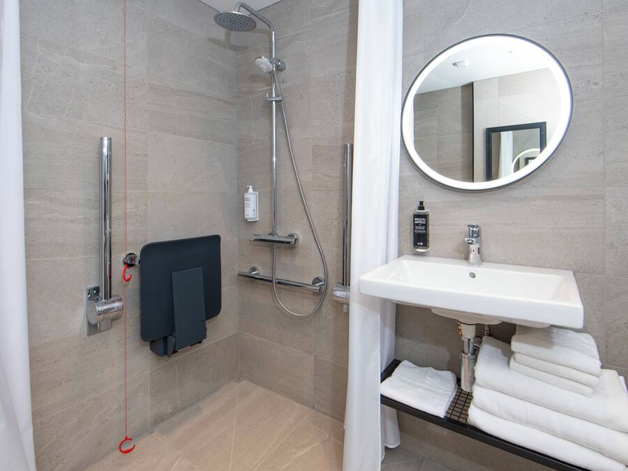 A modern bathroom with a shower, a sink, a mirror, and a towel rack.