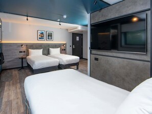 Une chambre d’hôtel avec deux lits, une télévision et une petite table.