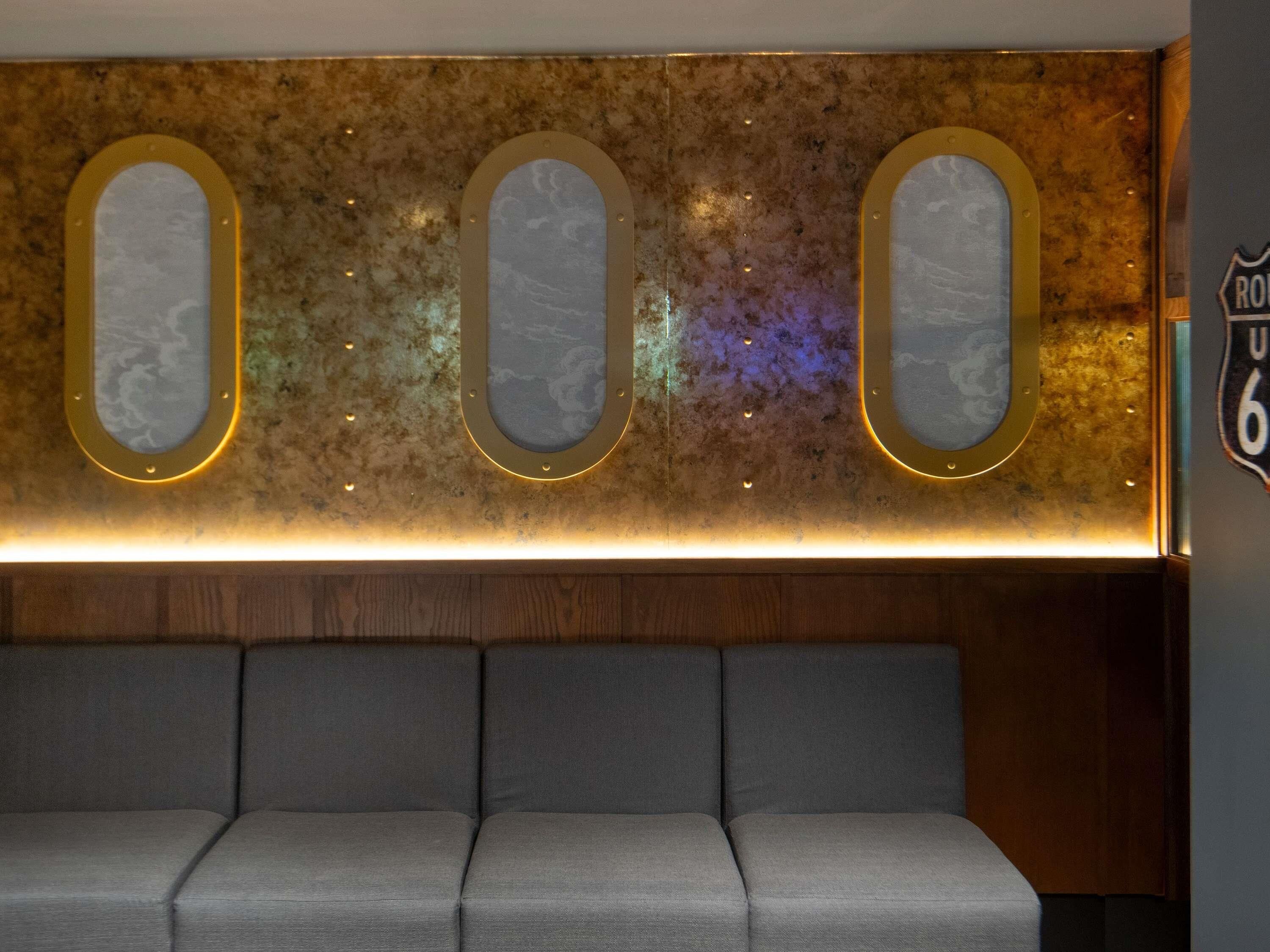 A seating area with a wall-mounted display featuring three oval frames with a marbled design and a neon light strip below.