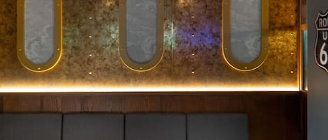 A seating area with a wall-mounted display featuring three oval frames with a marbled design and a neon light strip below.