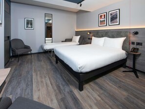 A modern hotel room with a large bed, bedside tables, a chair, and a mirror. - Ibis Styles London Gatwick Airport (Crawley)