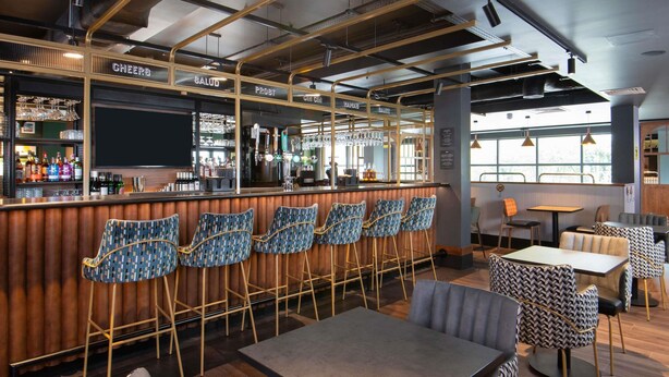 A bar area with a bar counter, multiple stools, and a seating area with tables and chairs.