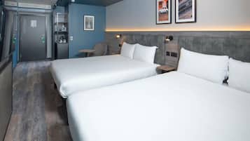 A hotel room with two beds, a desk, a chair, a small table, and a door.