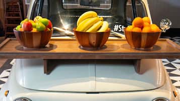 A vintage car with three wooden bowls of fruit on the hood.