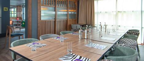 Un salón de conferencias con una larga mesa, sillas y vistas al exterior.