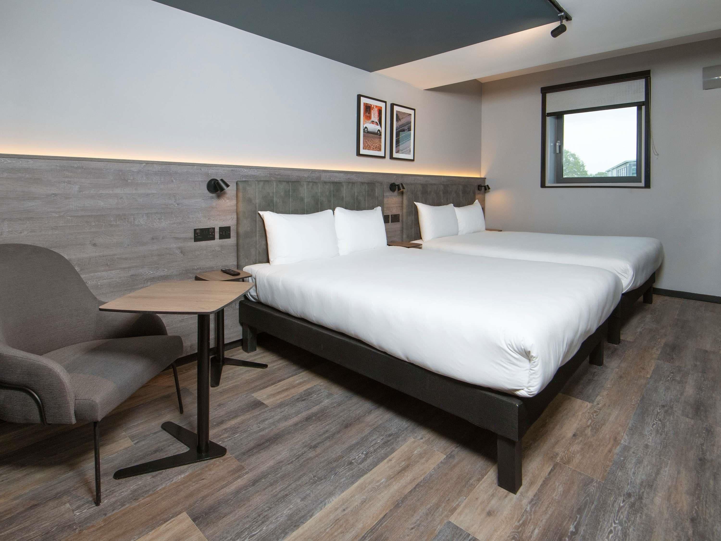 A modern hotel room with a large bed, a desk, and a chair.