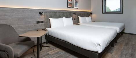 A modern hotel room with a large bed, a desk, and a chair.