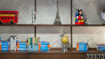 Una estantería con libros de viajes, un globo terráqueo, una réplica en miniatura de la Torre Eiffel, un autobús rojo y una figurita de Mickey Mouse.