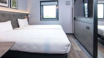 Quarto de hotel moderno com duas camas, uma janela grande e vista para o exterior.