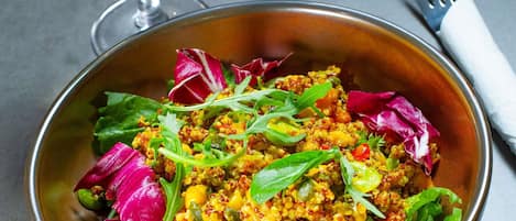 A bowl of quinoa salad with mixed vegetables and greens.