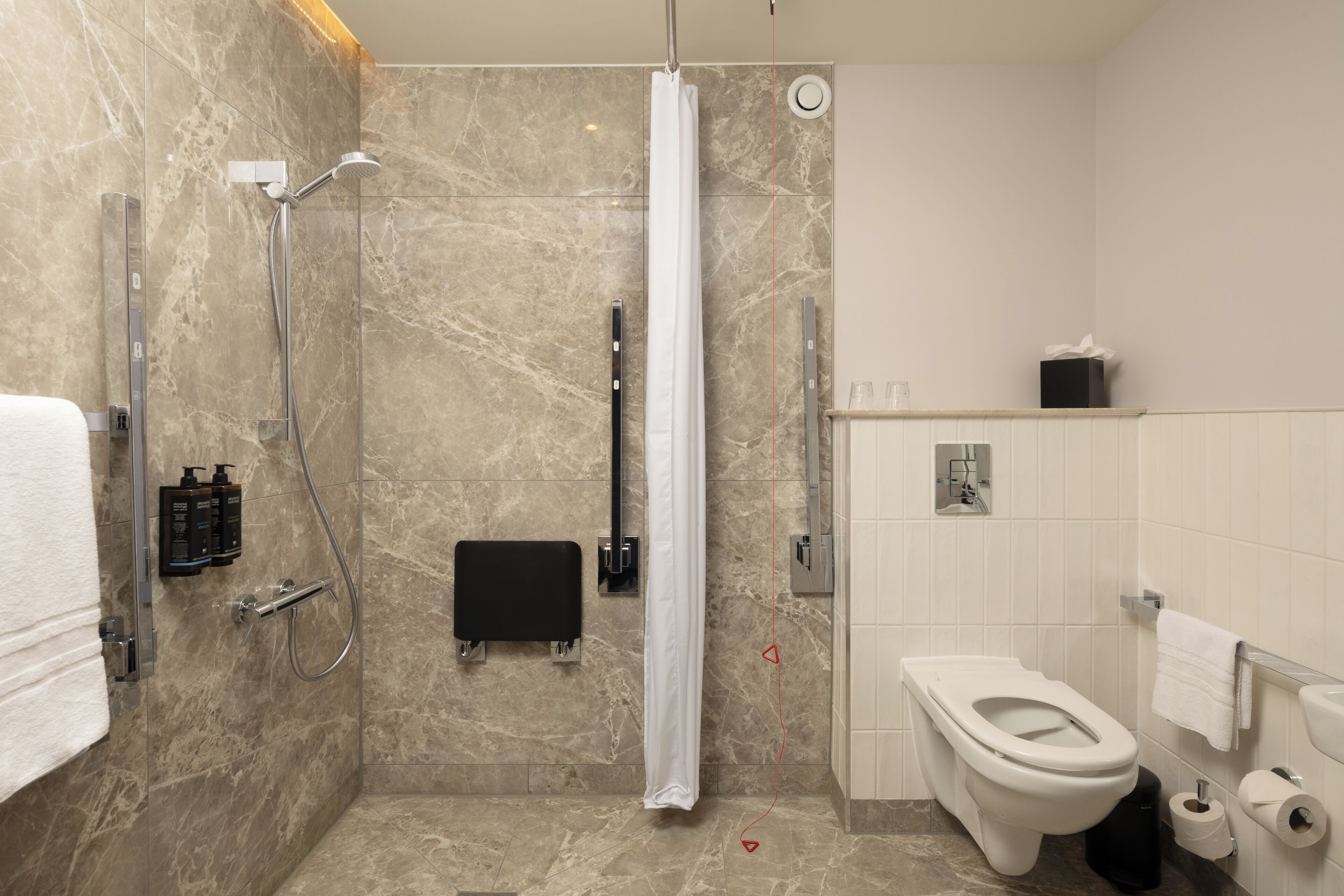 Un baño moderno con ducha, inodoro y secador de manos.
