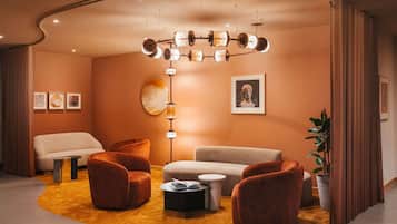 A modern living room with a curved ceiling, a central light fixture, a sofa, armchairs, a coffee table, and a potted plant.