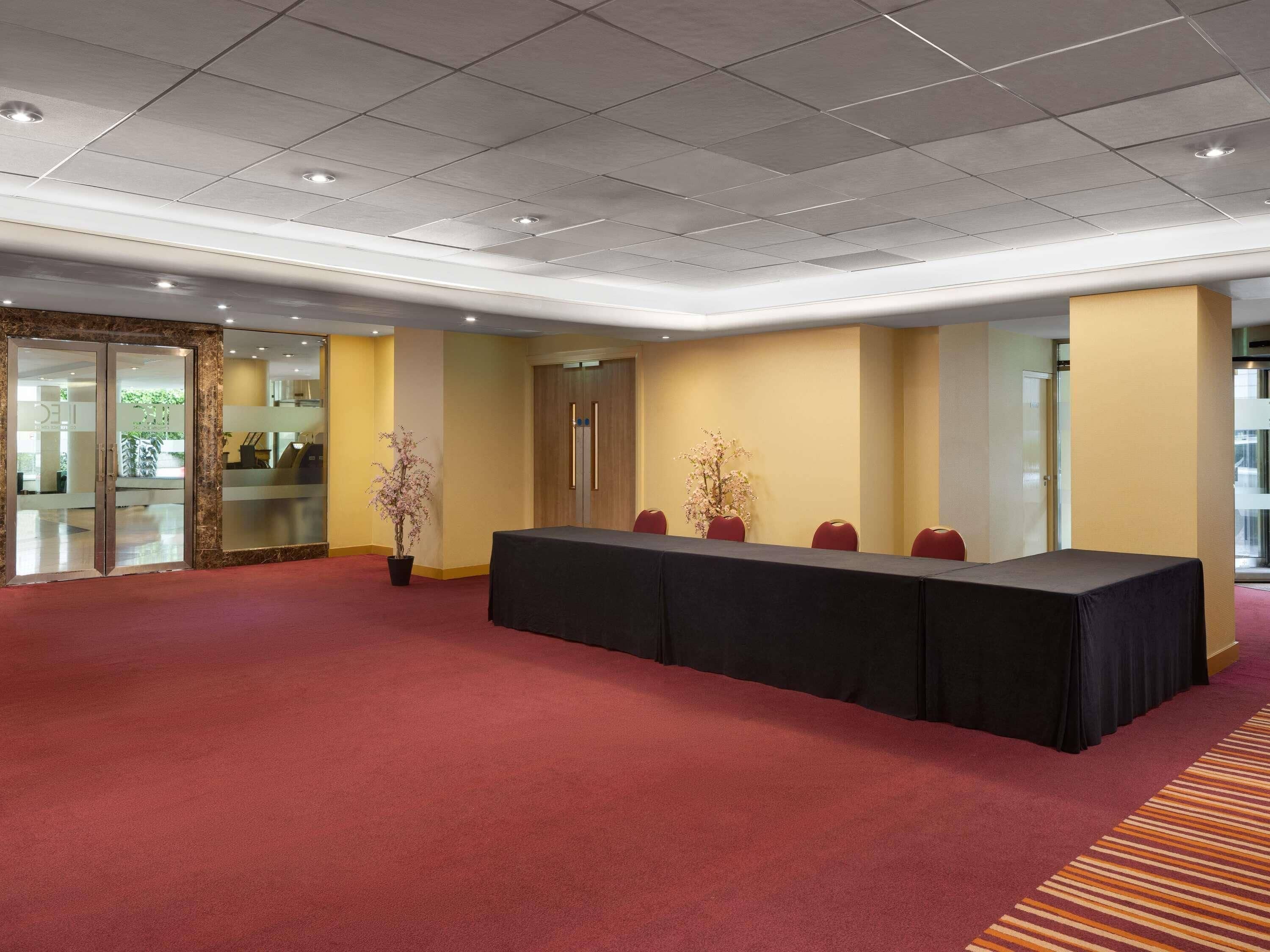 Une salle de conférence avec une longue table, des chaises et des plantes en pot.