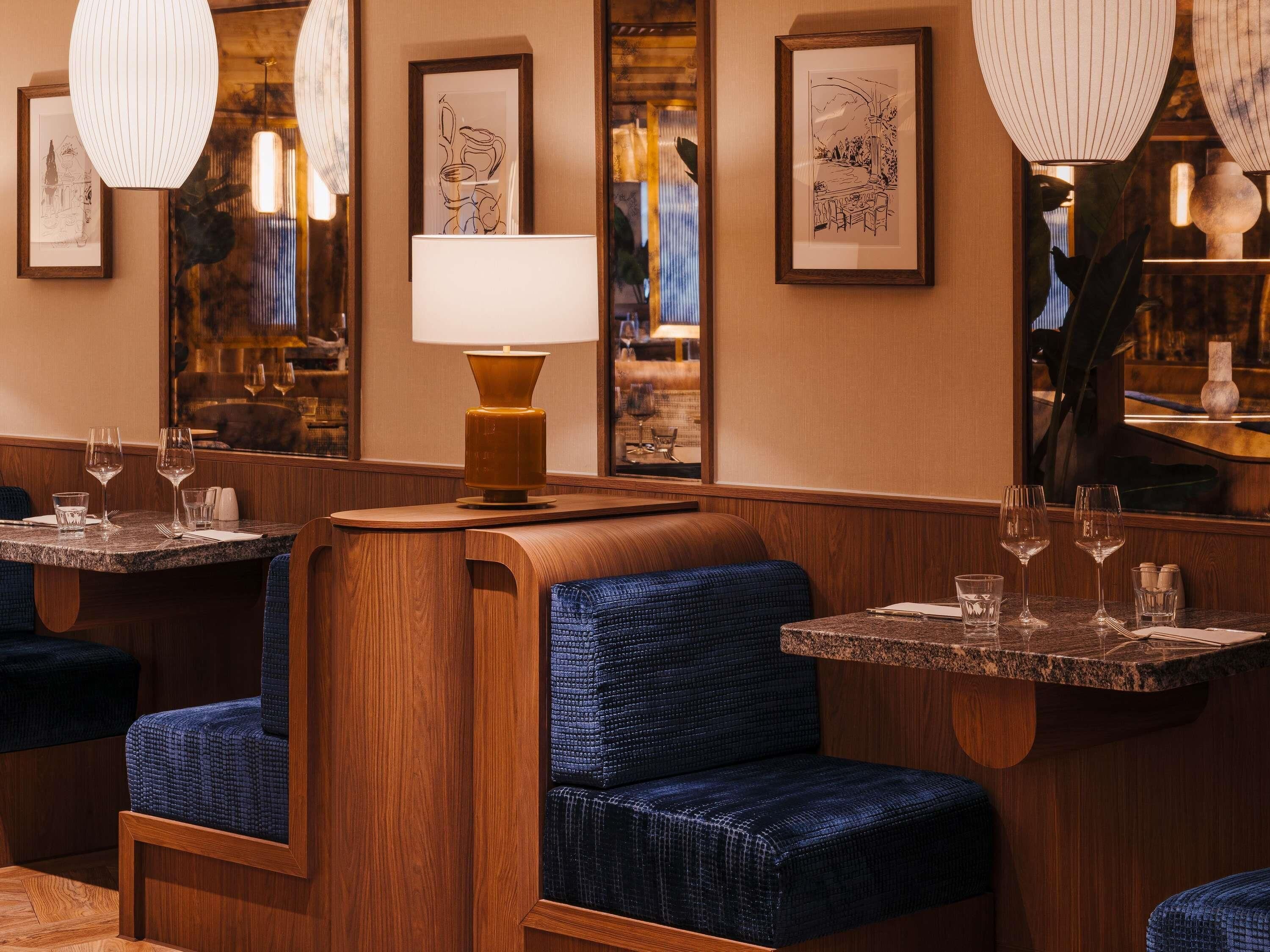 A restaurant interior with wooden booths, tables, and hanging lamps.