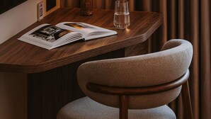 Et træbord med et magasin, et glas vand og en lampe.