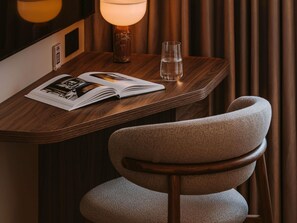 A wooden table with a magazine, a glass of water, and a lamp. - Mercure London Earls Court (London)