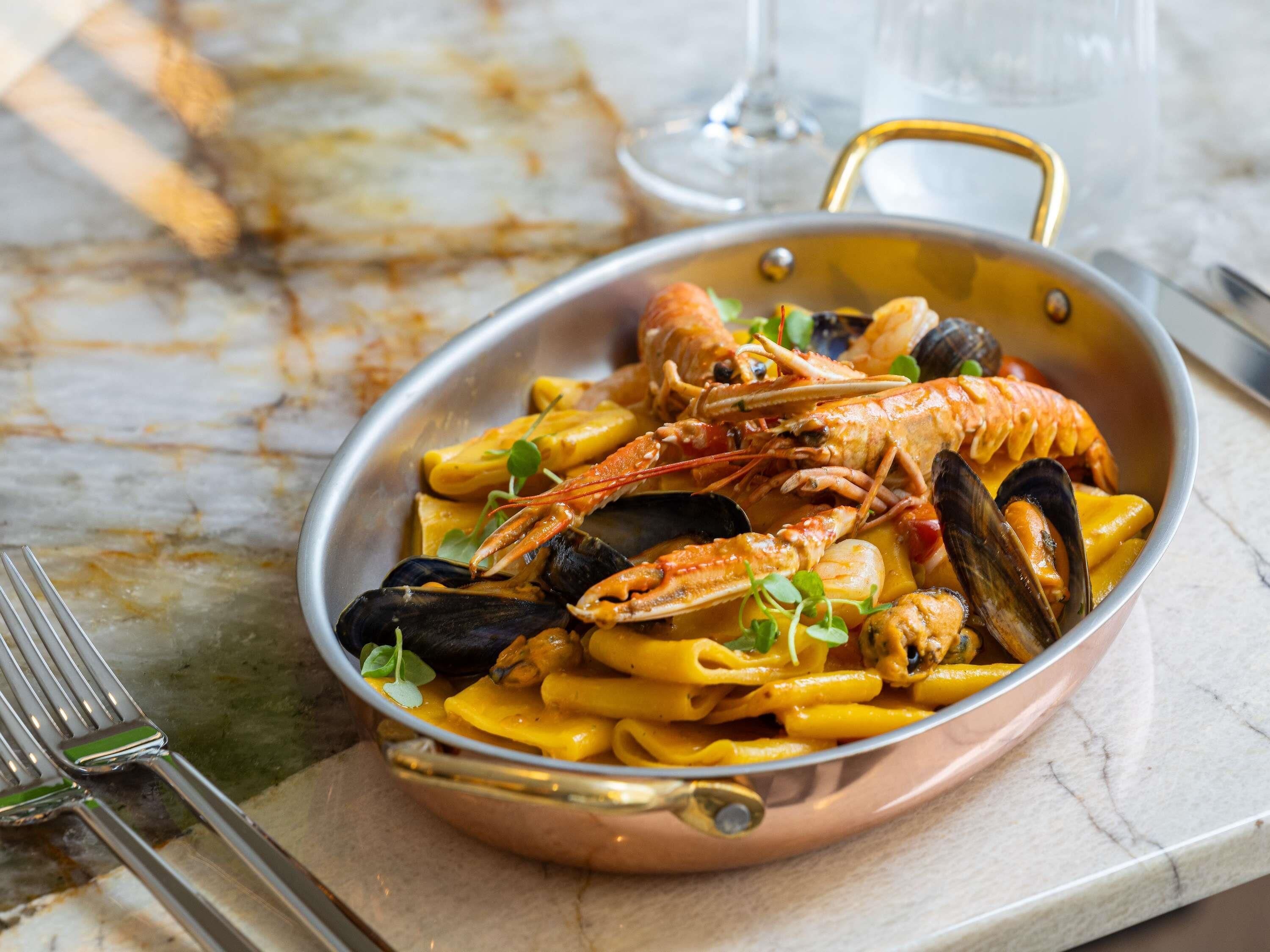 A seafood pasta dish in a copper pan.